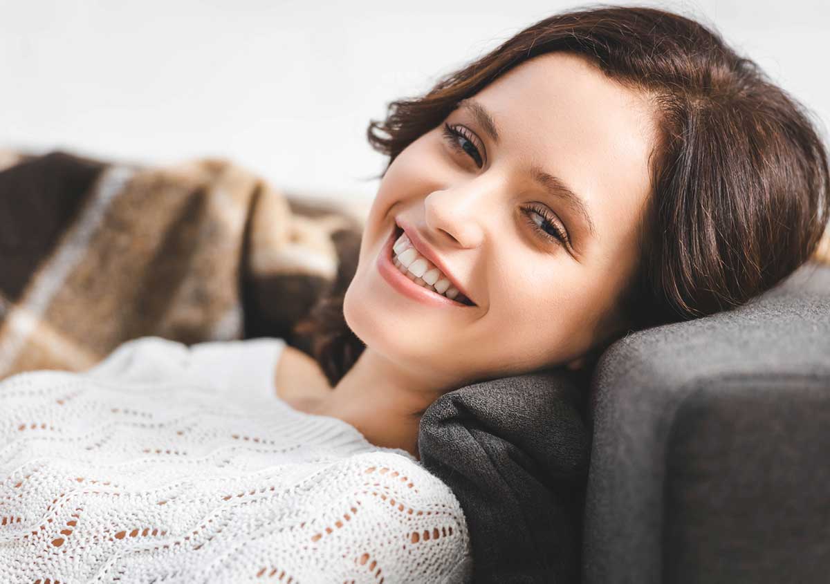 Woman smiling , leaning on sofa